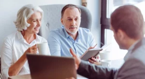 Couple senior en discussion avec un conseiller en prévoyance obsèques.
